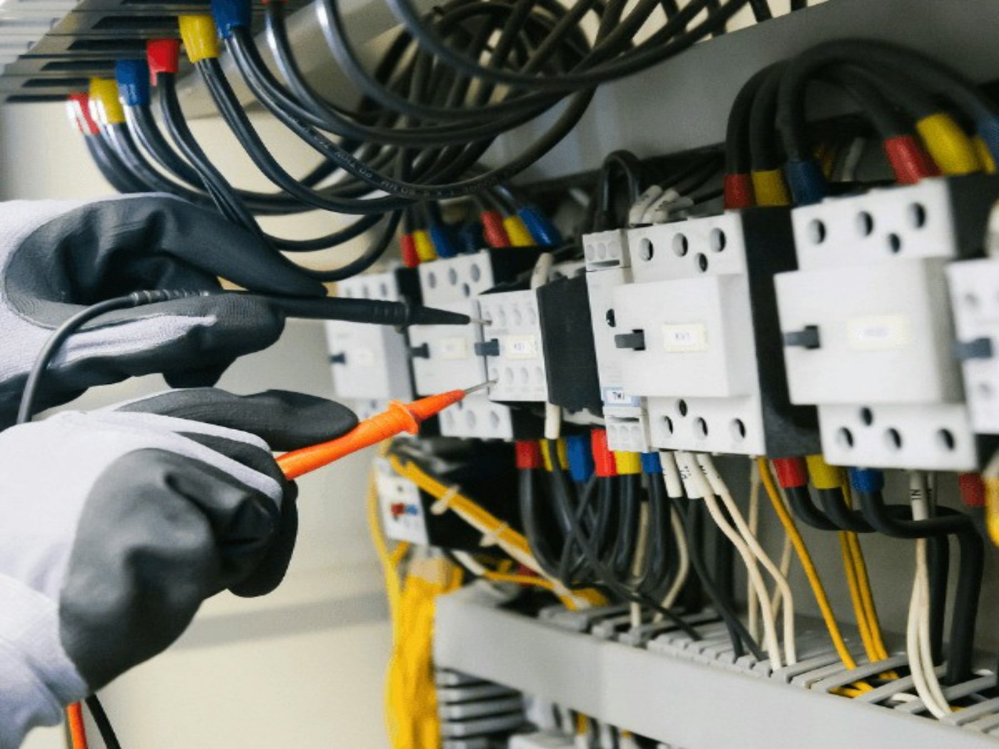 Técnico com luvas fazendo manutenção em um quadro elétrico