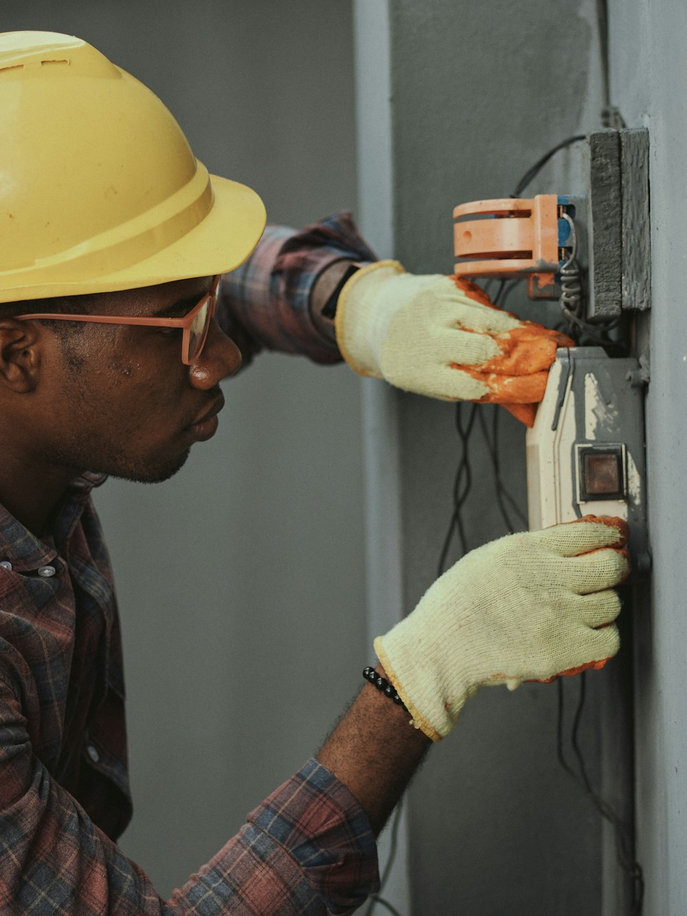 Técnico de manutenção com capacete testando um equipamento elétrico